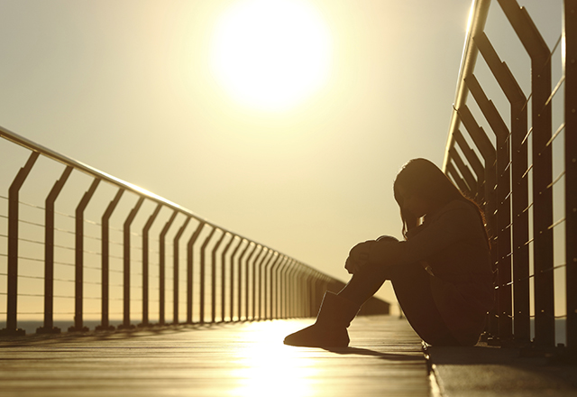 depressed woman sitting on a bridge